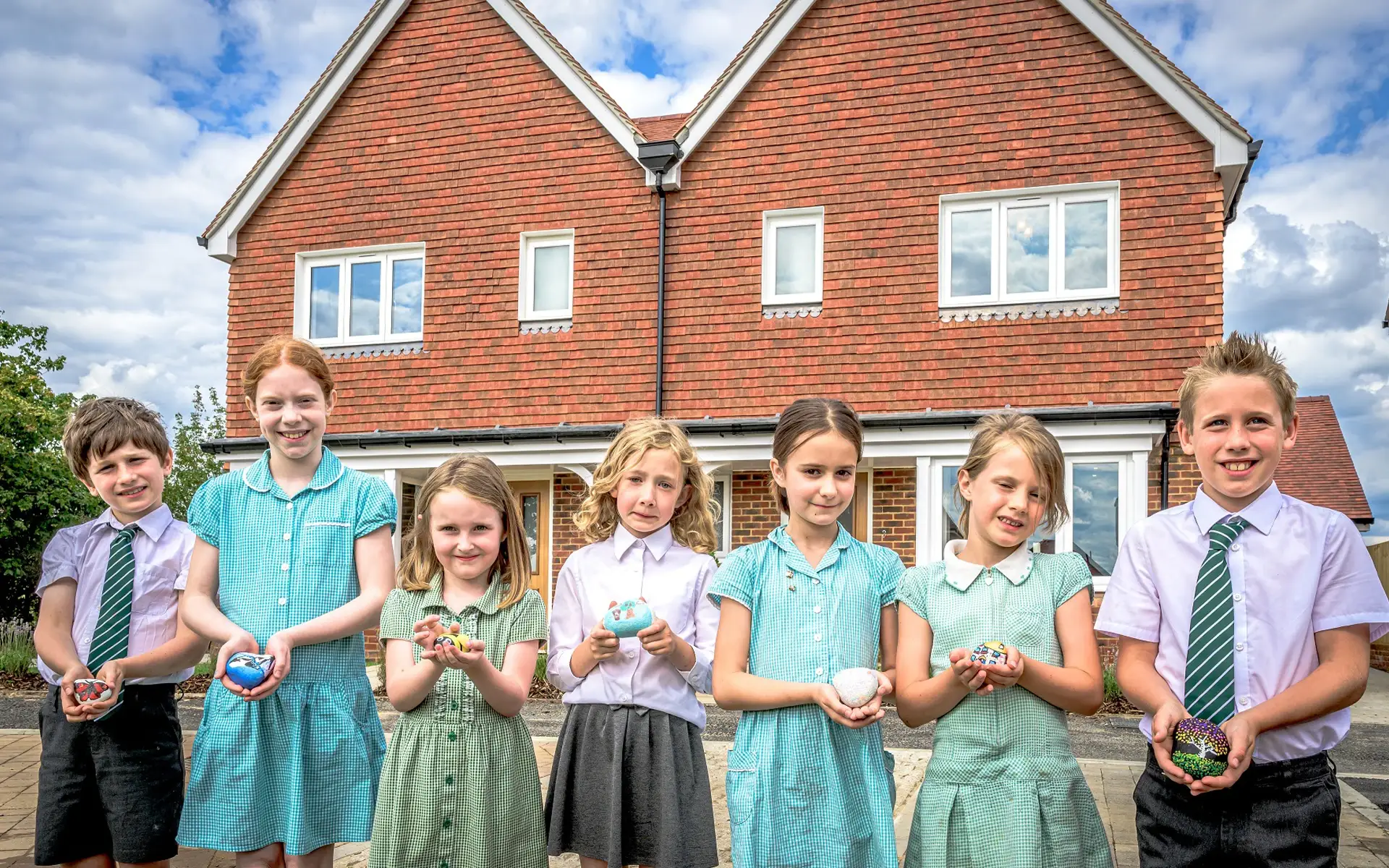 Raleigh school pupils smile and hold their stone painting artwork.