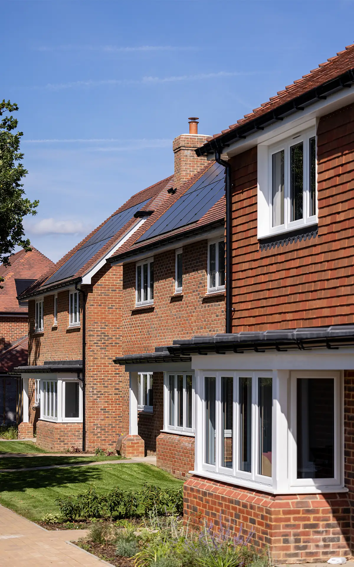 A row of three houses at Manorwood, West Horsley. Solar panels are found on each roof.